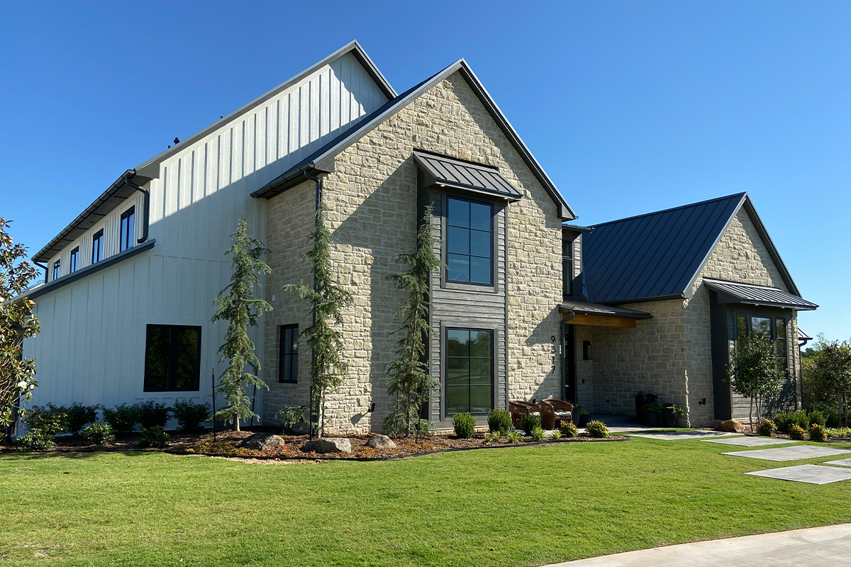 Modern home with light natural stone exterior and black metal roof.