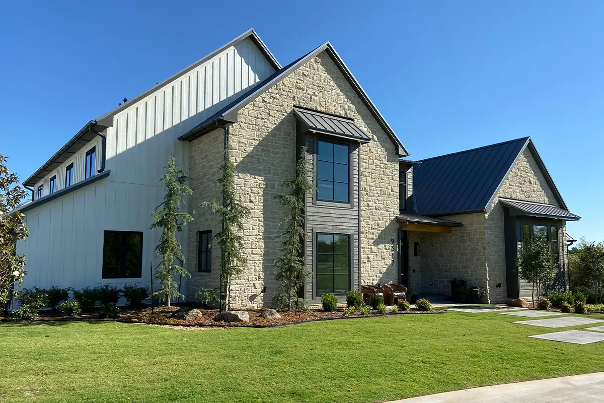 Modern home with light natural stone exterior and black metal roof